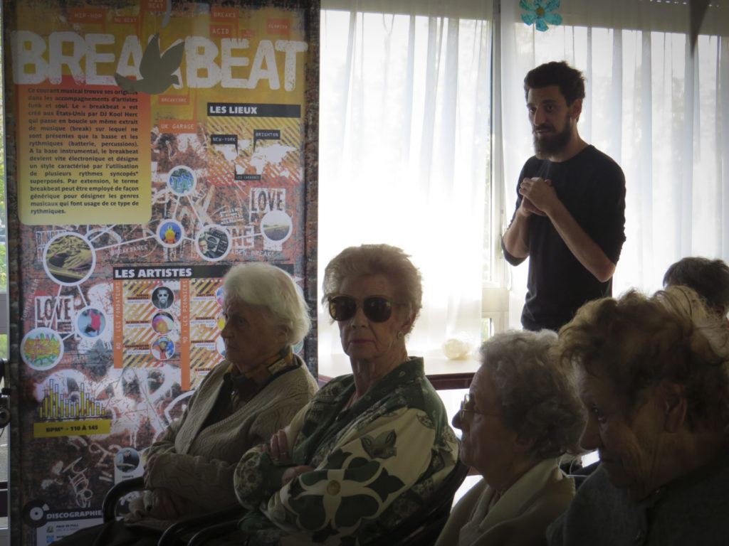 Des personnes âgées assis écoutant l'atelier sur les musiques électroniques