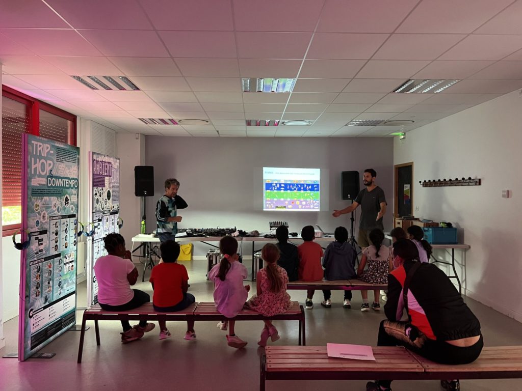 Des enfants assis écoutant l'atelier sur les musiques électroniques